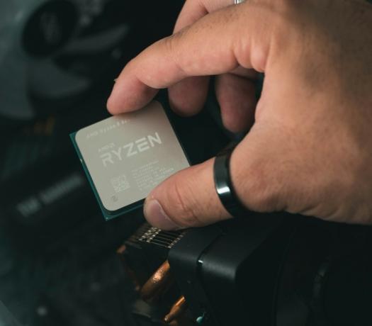 Крупный план человека, держащего процессор AMD Ryzen 5600X рядом с корпусом ПК.